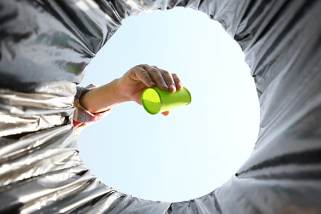 Man garbage throwing into trash bin outdoors, bottom view