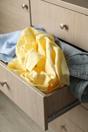 Cluttered chest of drawers, closeup. Clothes in mess