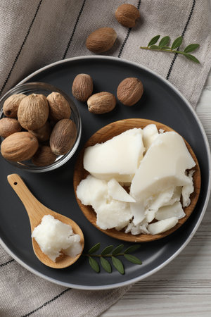 Natural shea butter, nuts and green leaves on wooden table, top viewの写真素材