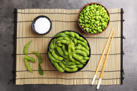 Raw green edamame soybeans and pods on gray table, top viewの写真素材