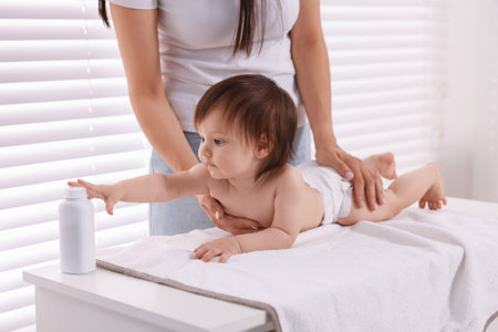 Mother changing her baby's diaper on table at home, closeupの写真素材