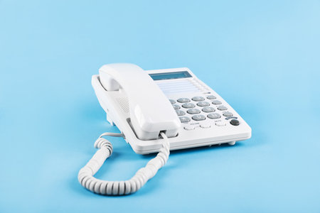 White telephone with handset on light blue backgroundの写真素材