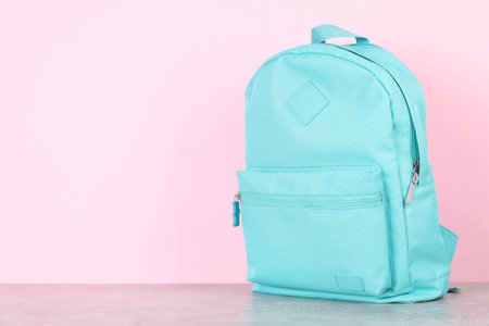 Light blue backpack on gray table against pink background. Space for textの写真素材