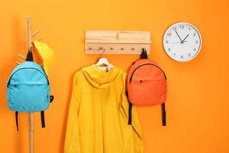 Bright backpacks, cap, coat and clock near orange wallの写真素材