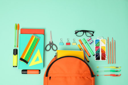 Backpack and different school supplies on turquoise background, flat layの写真素材