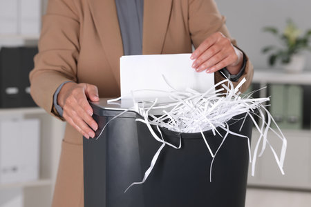 Woman destroying paper with shredder in office, closeupの写真素材