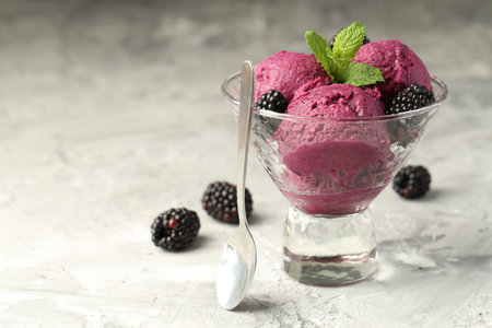 Delicious blackberry sorbet with fresh berries in bowl and spoon on gray textured table, space for textの写真素材