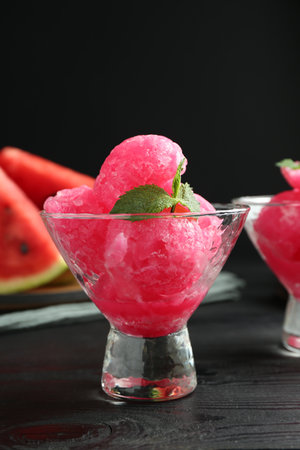 Tasty watermelon sorbet with mint in glass dessert bowls on black wooden table, closeupの写真素材