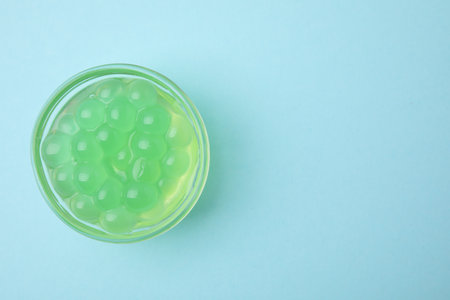 Bright tapioca pearls in bowl on light blue background, top view. Space for textの写真素材
