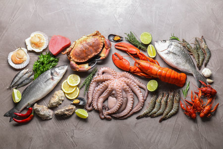Many different sea food, herbs, lemon and lime on gray textured table, flat layの写真素材
