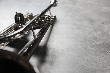 Closeup view of shiny trumpet on gray textured table, space for text. Wind musical instrument