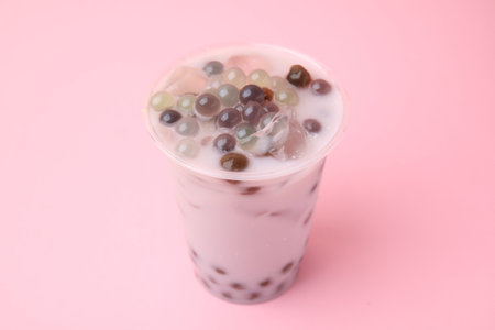 Tasty milk bubble tea in plastic cup on pink background, closeupの写真素材