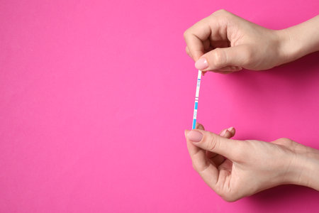 Woman holding pregnancy test on pink background, top view. Space for textの写真素材