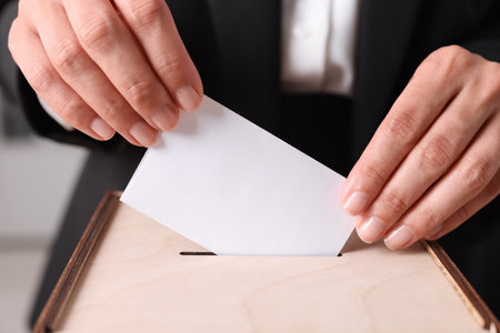 Woman putting her vote into ballot box indoors, closeupの写真素材