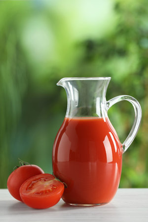 Tasty tomato juice in glass jug and fresh vegetables on white table outdoorsの写真素材