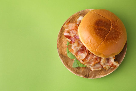 Delicious burger with bacon and greens on green table, top view. Space for textの写真素材
