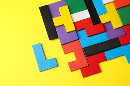 Colorful wooden puzzle pieces on yellow background, top viewの写真素材
