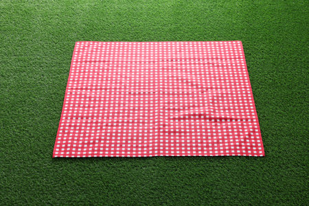 Red checkered picnic tablecloth on green grass
