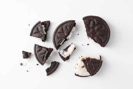 Broken tasty sandwich cookies on white background, flat lay