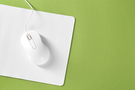 Wired mouse and mousepad on green background, top view. Space for textの写真素材