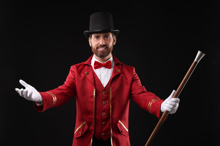 Portrait of showman in red costume and hat on black background