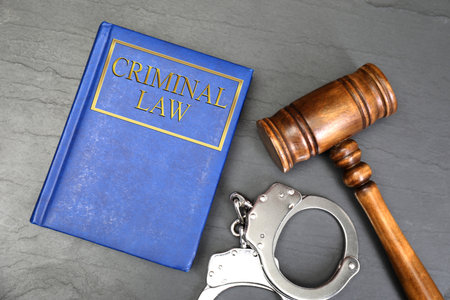 Book Criminal Law, judge's gavel and handcuffs on gray table, flat layの写真素材