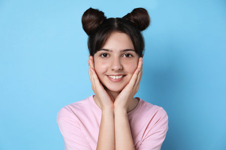 Portrait of smiling teenage girl on light blue backgroundの写真素材