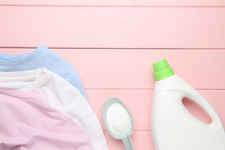 Laundry detergents and t-shirts on pink wooden table, flat layの写真素材