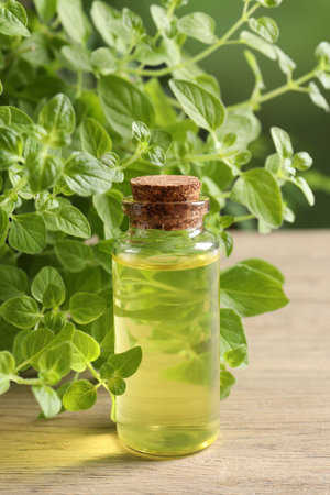 Essential oil in bottle and oregano leaves on wooden table, closeupの写真素材