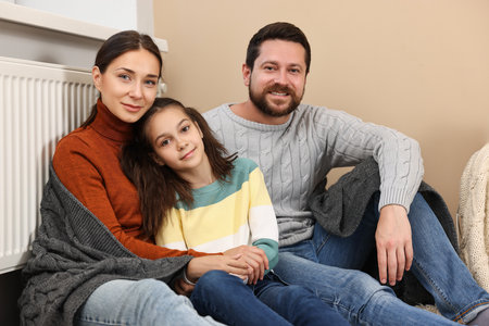 Happy family near heating radiator at homeの写真素材