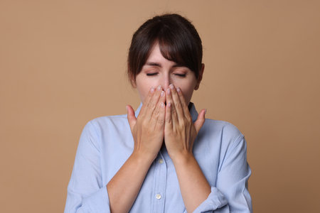 Woman suffering from sinusitis on beige backgroundの写真素材