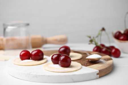 Process of making dumplings (varenyky) with cherries. Raw dough and ingredients on white tableの写真素材