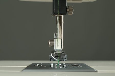 Sewing machine with green thread on grey background, closeupの写真素材