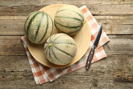 Ripe Cantaloupe melons and knife on wooden table, flat layの写真素材