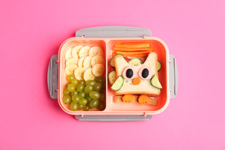 Lunch box with sandwich and fruits on pink background, top viewの写真素材