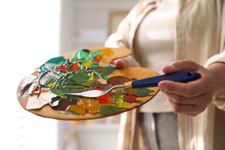 Woman with knife using palette indoors, closeupの写真素材