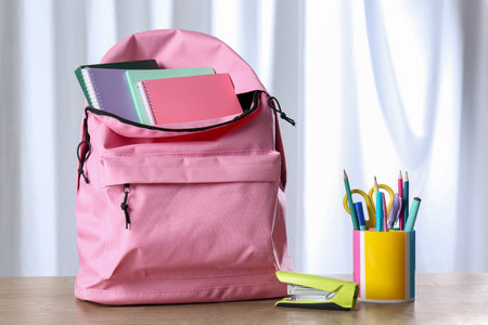 Backpack with different school stationery on wooden tableの写真素材