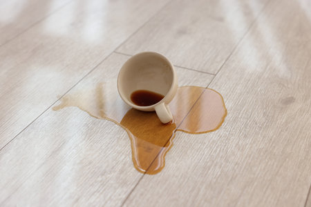 Cup with spilled drink on wooden floor, closeupの写真素材
