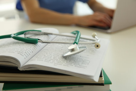 Doctor at white table in hospital, focus on medical stethoscope and booksの写真素材