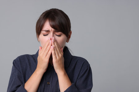 Woman suffering from sinusitis on grey background. Space for textの写真素材