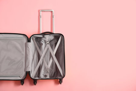 Open empty suitcase on pink background, top view. Space for text