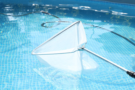 Cleaning swimming pool with skimmer net, closeup