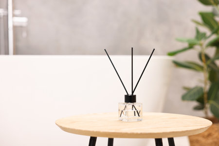 Reed diffuser on wooden table in bathroom, space for textの写真素材