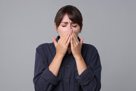Woman suffering from sinusitis on grey backgroundの写真素材