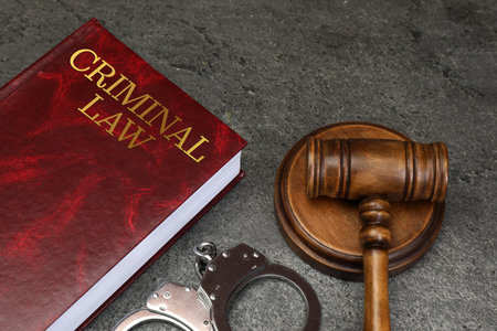 Book Criminal Law, judge's gavel and handcuffs on grey tableの写真素材