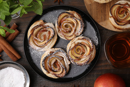 Freshly baked apple roses, ingredients and tea on wooden table, flat layの写真素材