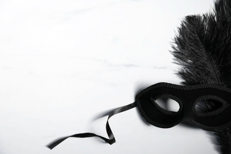 Beautiful black carnival mask on white marble table, space for textの写真素材