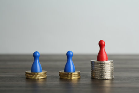 Financial inequality. Human figures and coins on wooden tableの写真素材