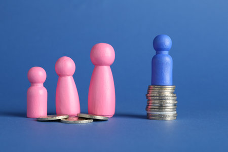 Financial inequality. Male and female figures with uneven amount of coins on blue backgroundの写真素材