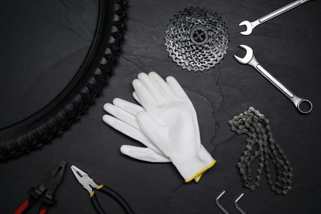 Flat lay composition with different bicycle components, tools and gloves on dark gray textured backgroundの写真素材